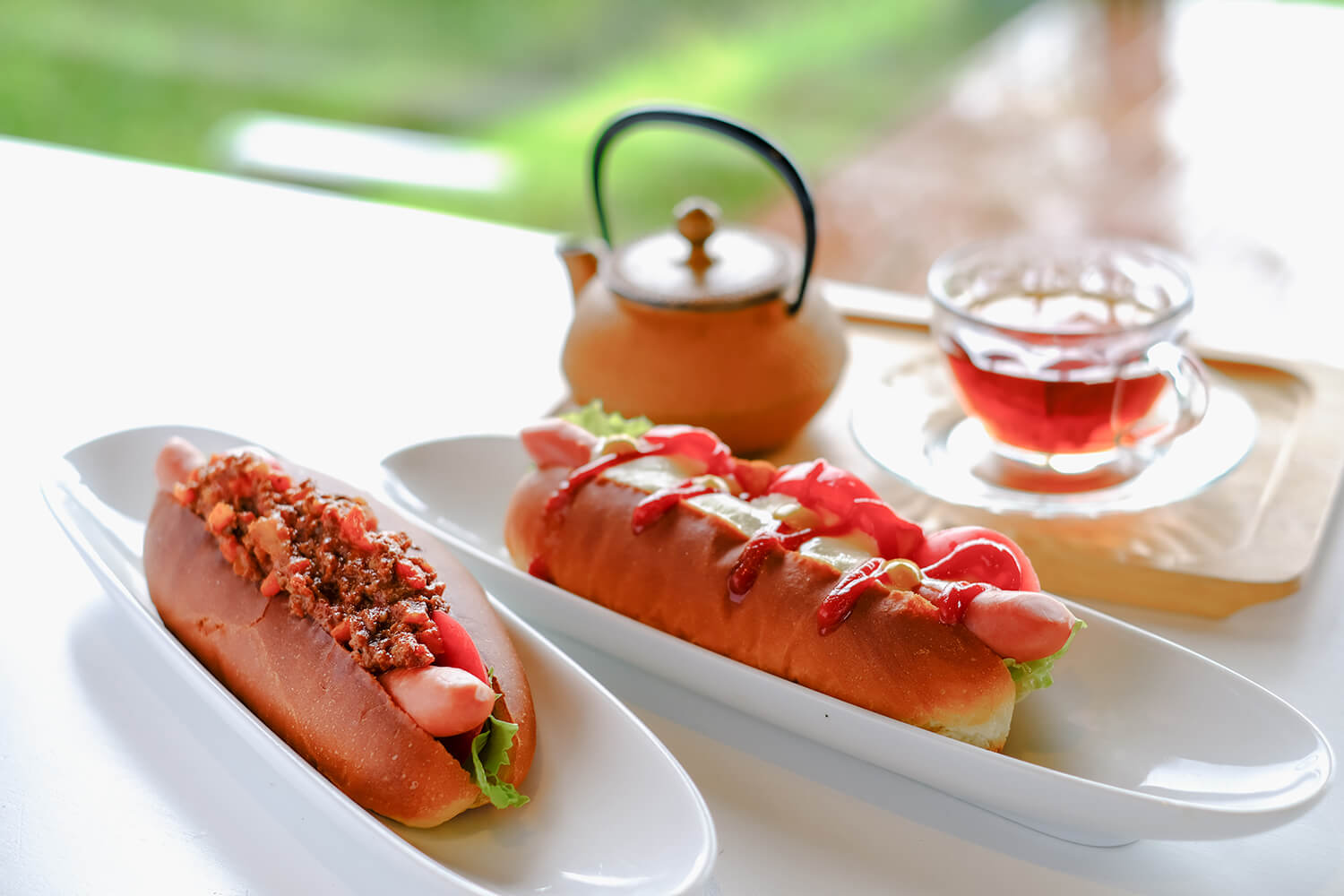 「峇里島熱狗」（JPY480）在左邊，「起司熱狗」（JPY450）在中間。 「永田紅茶」用鐵鍋盛用（400日圓）