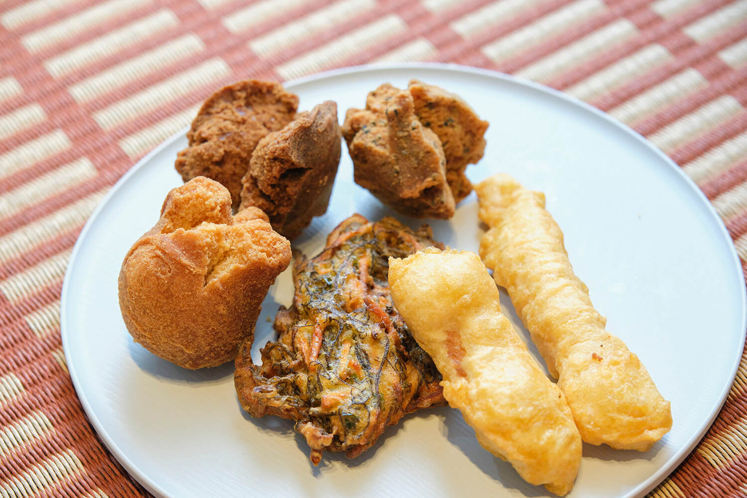 從左起順時針方向，「Sutter Andagi（原味、黑糖、芝麻）」各90日圓、「魷魚天婦羅」、「海蘊天婦羅」