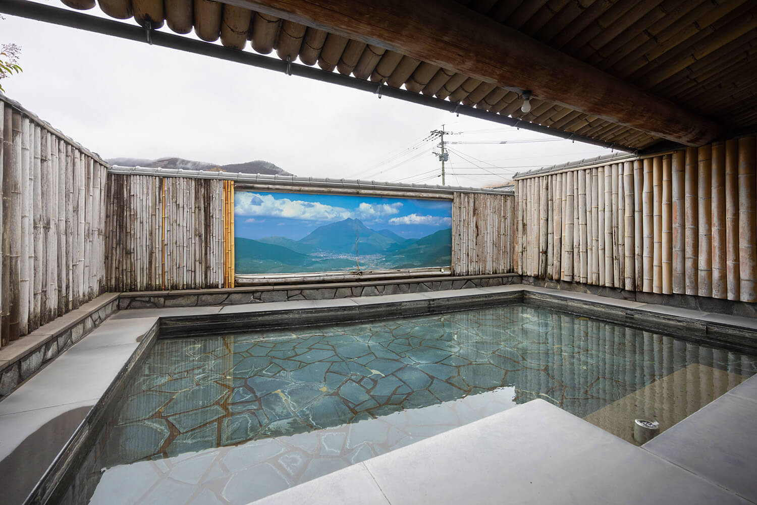 露天溫泉，配有石製浴缸。 晴天時，你可以在城牆後看到夕布山