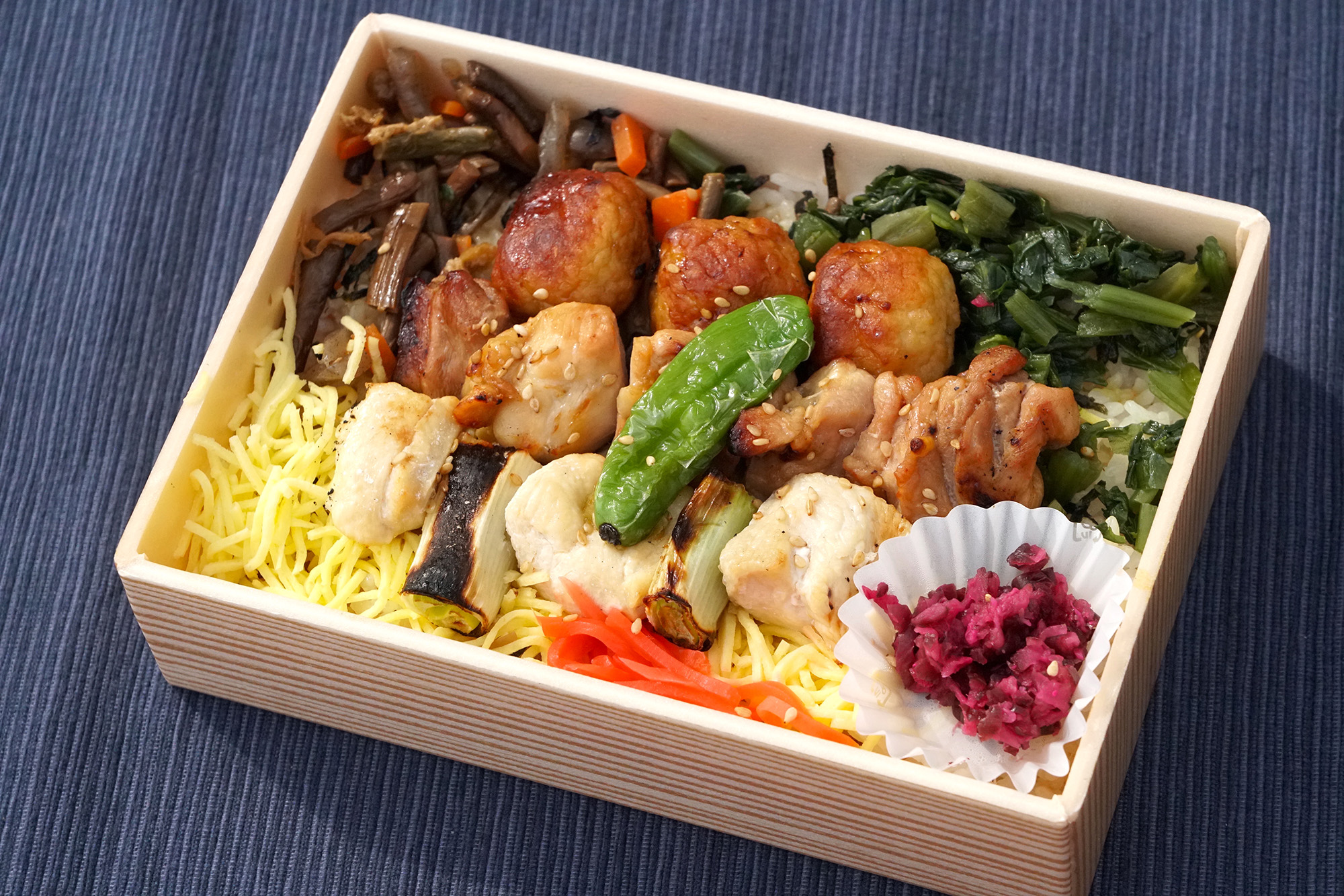 「炭烤雞肉野菜便當」上面放著肉、烤雞肉串、雞肉丸和野菜的米飯JPY1100