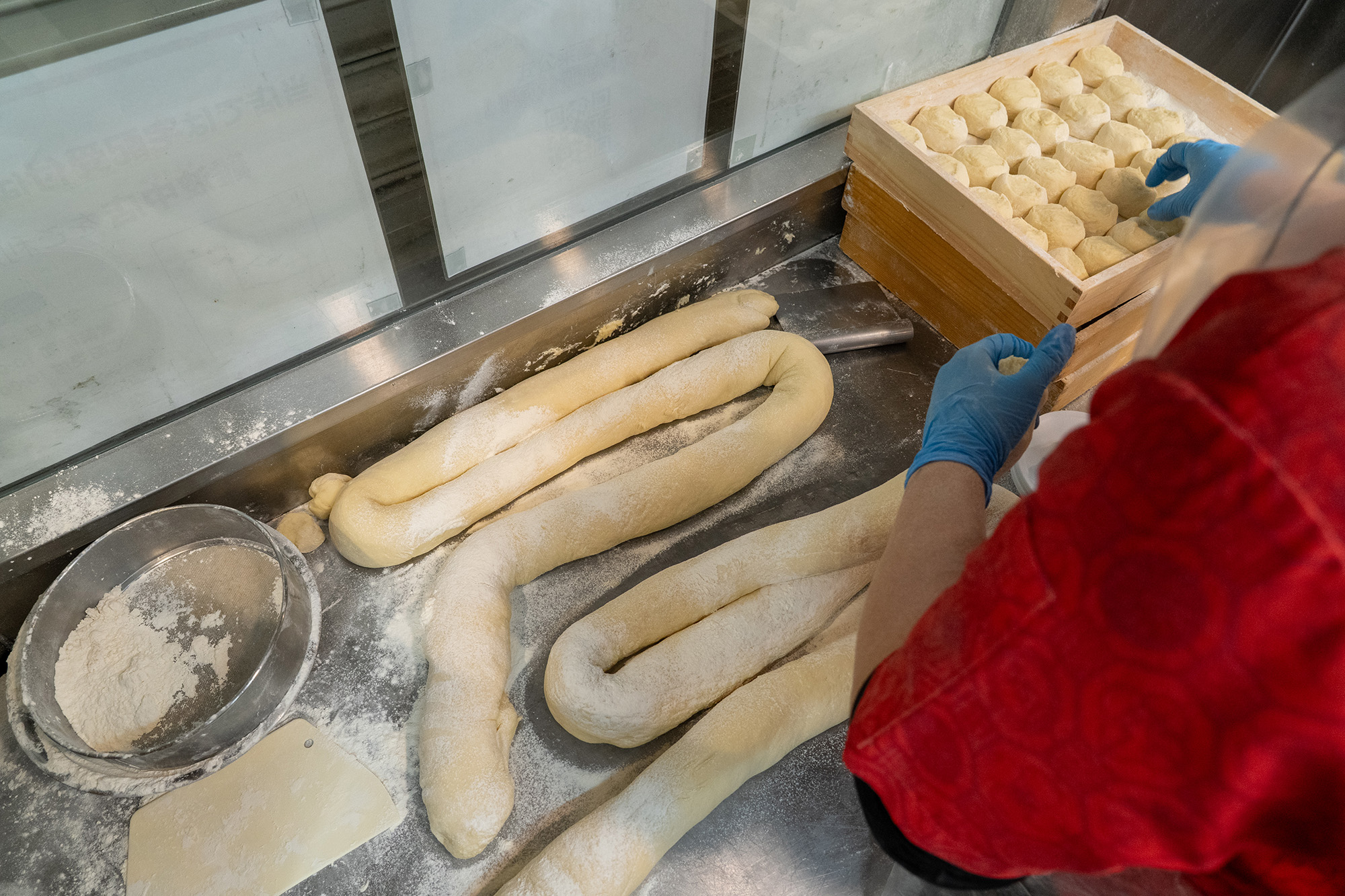 將中央廚房送來的麵糰手工揉好後，稱重後分成小份，進行二次發酵