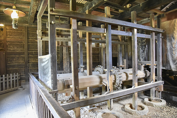 藩米精米所。水車で木製の歯車が回り、木の棒が米をつく仕組み