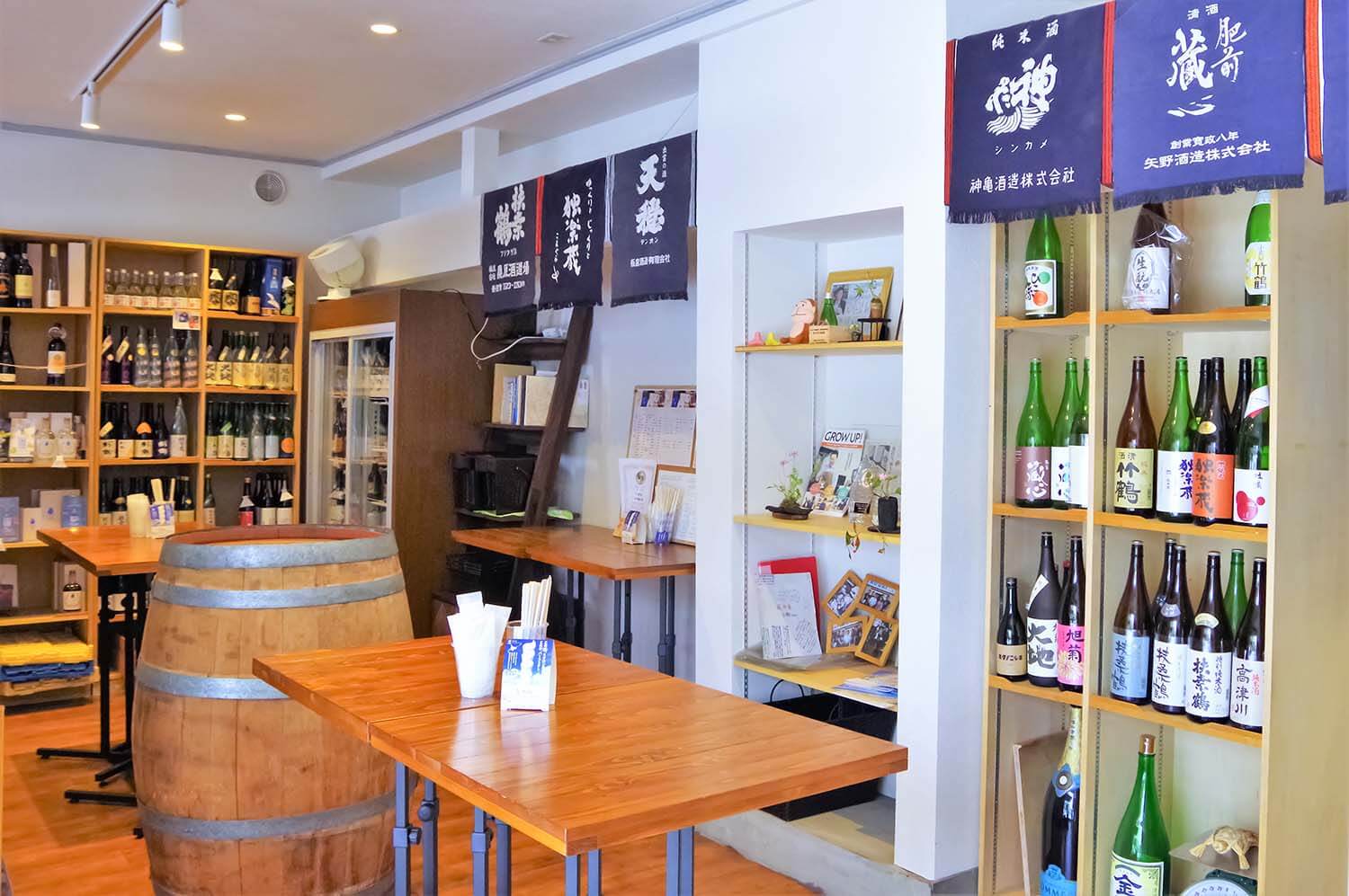 日本酒がずらりと並ぶ店内の中央に角打ちのテーブルが並ぶ。支払いはキャッシュオン制