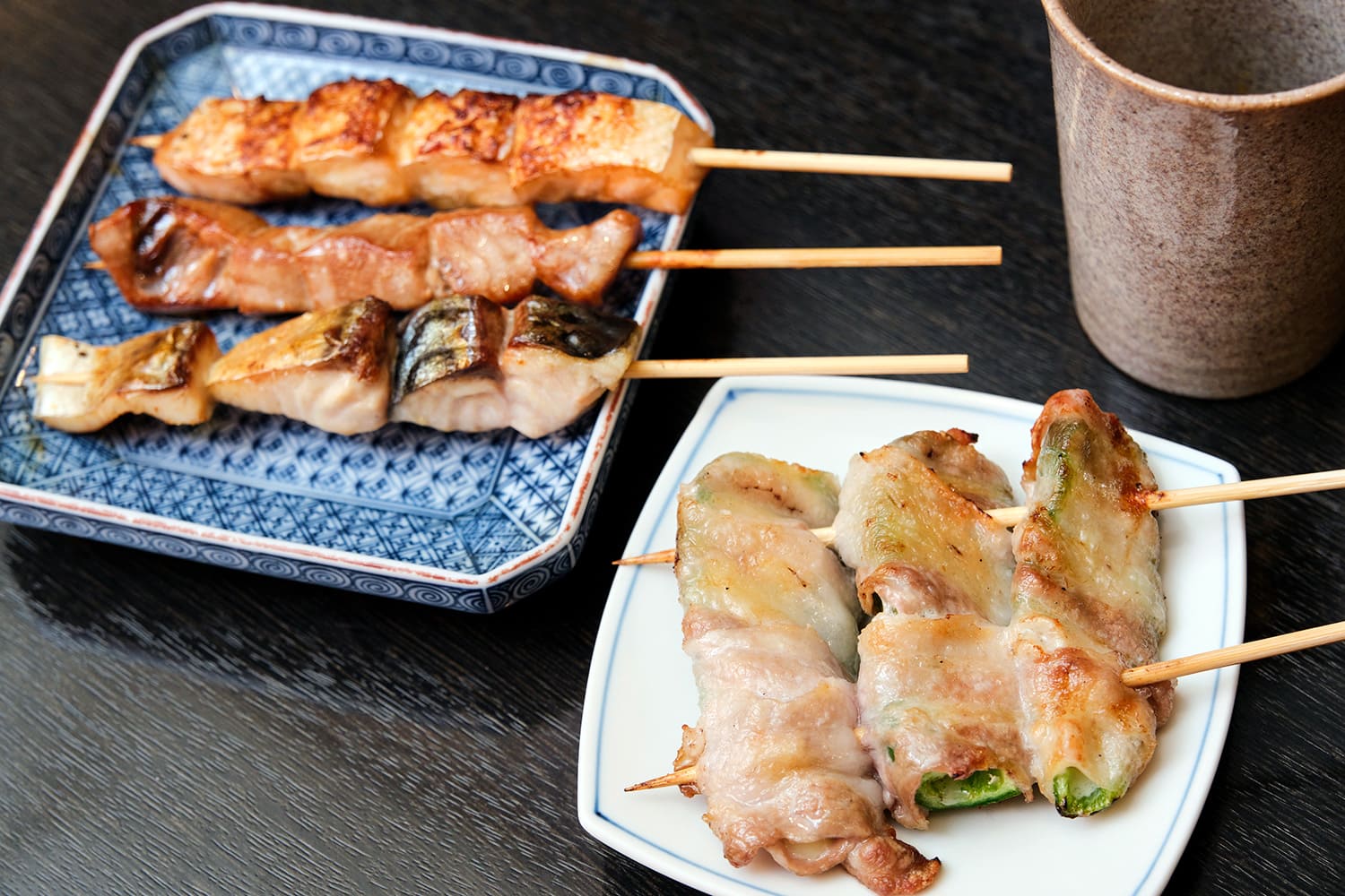 魚の串焼き（左）は、手前からサバ、マグロの脳天、鮭ハラス各200円。「ピーチー」（右）は1本300円